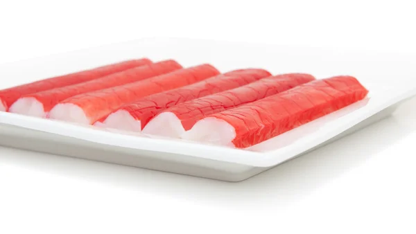 Varas de surimi em uma placa quadrada isolada em branco — Fotografia de Stock