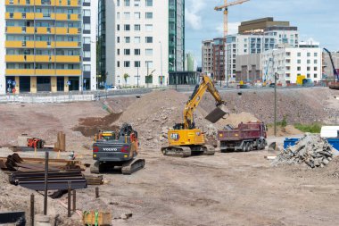 Espoo, Finlandiya - 1 Ağustos 2025: Meritie Caddesi 'nde bir inşaat sahası, yeni bir yol, ilerleme, mühendislik ve modern kentsel altyapı geliştirme inşasında ağır makineler aktif olarak çalışıyor