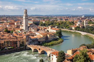 İtalya 'nın Verona kentinin hava manzarasında Duomo di Verona ve Adige Nehri' ni geçen antik Ponte Pietra köprüsü, kırmızı kiremitli çatılar ve Veneto bölgesinin tarihi kalbiyle çevrilidir.