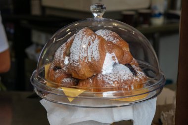 İtalya, Verona - 1 Ekim 2025: İtalya 'da bir kafe penceresinde taze kruvasanlar sergilendi, kahve için altın, pullu hamur işleri, İtalyan kahvaltı kültürünün cazibesini yansıtıyor.