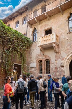 İtalya, Verona - 1 Ekim 2025: Turistler aşkın simgesi ve en romantik simgelerinden biri olan Casa di Giulietta 'nın balkonunun altındaki Juliet heykelinin yanında toplandı.