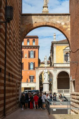 İtalya, Verona - 1 Ekim 2025: Turistler Piazza dei Signori 'deki Dante Alighieri heykelinin yanında toplanarak güneşli günün ve zengin kültürel atmosferin tadını çıkardılar.