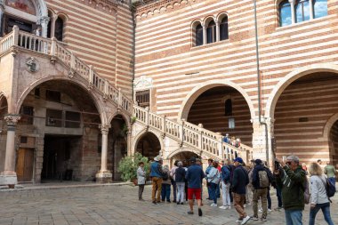 İtalya, Verona - 1 Ekim 2025: Scala della Ragione (Adalet Merdiveni) Palazzo della Ragione 'nin avlusunda, Gotik kırmızı mermer merdiveni üzerinde turistler tarihi mekanı keşfediyor.