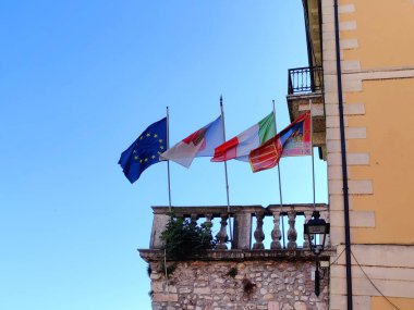 Avrupa Birliği, Veneto bölgesi ve İtalya 'nın bayrakları Veneto, İtalya' da bir balkonda dalgalanıyor. Aydınlık bir günde rüzgarda sallanan üç renkli renkler ve semboller
