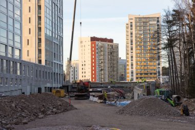 Espoo, Finlandiya - 20 Kasım 2025: Meritie, köprü ve yürüyüş yolu inşaatı sırasında ağır makinelerle çalışan karayolu geliştirme Finnoo metro istasyonu, konut binaları