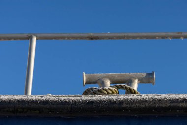 Teknede krampona bağlanmış eski bir ip. Arka planda mavi, temiz bir deniz olan denizcilik halatı..