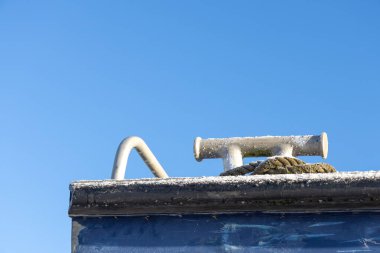 Teknede krampona bağlanmış eski bir ip. Arka planda mavi, temiz bir deniz olan denizcilik halatı..