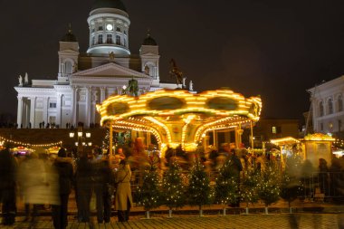 Helsinki, Finlandiya - 22 Aralık 2025: Senato Meydanı 'nda Helsinki Noel Pazarı Tuomaan Markkinat arka planda Tuomiokirkko, tatil ışıkları, Finlandiya yemekleri, el sanatları, atlıkarınca, ziyaretçiler