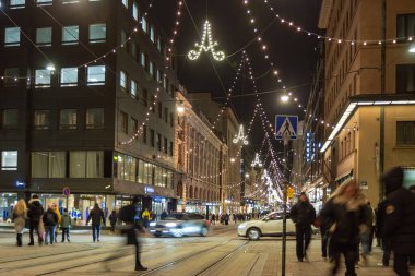 Helsinki, Finlandiya - 22 Aralık 2025: Aleksanterinkatu Noel için aydınlatıldı. Festivalin ışıklarıyla süslenmiş ana alışveriş caddesi, kış tatillerinde yerli ve turistlerin ilgisini çekiyor