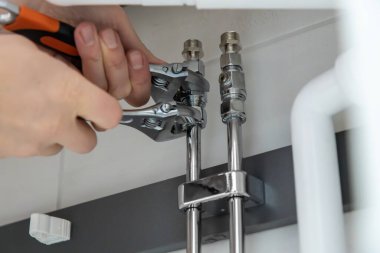 Tesisat işi yapan ellerin yakın çekimi, iki anahtarla boru tesisatını sıkılaştırmak. Güvenli bağlantılar ve düzgün bakım sağlanması için profesyonel kurulum veya onarım görevi