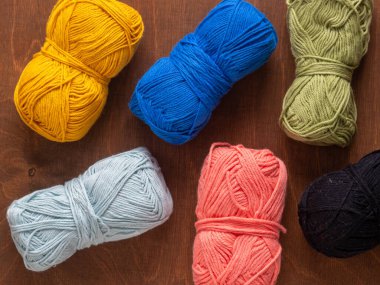 Örgü örmek ya da örmek için renkli eko pamuk iplikleri. Koyu ahşap bir arka plana yerleştirilmiş. Yukarıdan aşağıya görünümlü el yapımı el yapımı malzemeler