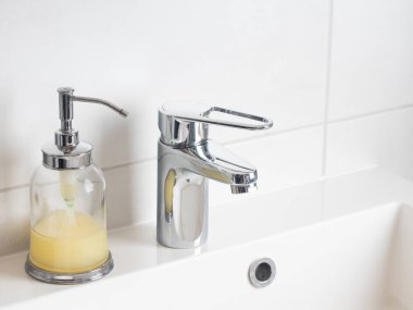 El yıkama ve hijyen konsepti. Cam makinesinde sıvı dezenfektan sabun ve banyoda musluk suyu, kapat. Kişisel hijyen, sağlık hizmetleri ve koronavirüs önleme