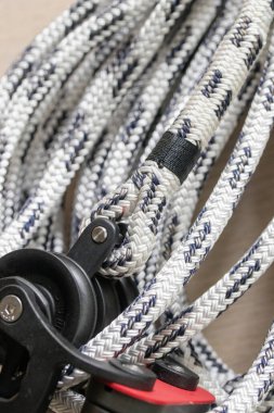 Siyah izleyicilerle bembeyaz sarmalanmış çift örgülü deniz polyester halatının yakın plan fotoğrafı, kilit prangasına bağlanmış ve bloklanmış. Yelkencilik, tekne ve deniz kullanımı için ideal.