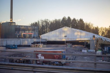 Espoo, Finlandiya - 12 Aralık 2025: Finnoo 'daki Meritie caddesinde, bitmemiş yapıyı hava durumundan korumak için geçici bir kumaş barınağı (branda) bulunan bir inşaat sahası