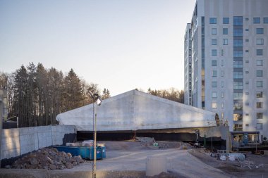 Espoo, Finlandiya - 12 Aralık 2025: Finnoo 'daki Meritie caddesinde, bitmemiş yapıyı hava durumundan korumak için geçici bir kumaş barınağı (branda) bulunan bir inşaat sahası