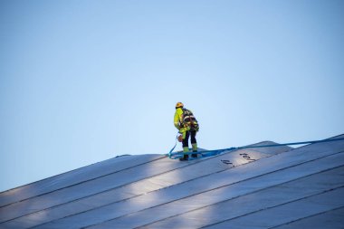 Espoo, Finlandiya - 12 Aralık 2025: Finnoo inşaat Meritie karayolundaki bir alanı kaplayan büyük beyaz bir geçici kumaş barınağının üzerinde güvenlik teçhizatı kullanan bir inşaat işçisi duruyor