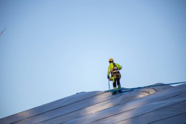 Espoo, Finlandiya - 12 Aralık 2025: Finnoo inşaat Meritie karayolundaki bir alanı kaplayan büyük beyaz bir geçici kumaş barınağının üzerinde güvenlik teçhizatı kullanan bir inşaat işçisi duruyor