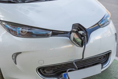 Avrupa tip 2 elektrikli araç şarj portu beyaz bir arabaya entegre edilmiş, AC şarj kablosu bağlı, modern EV şarj teknolojisi, sürdürülebilir ulaşım