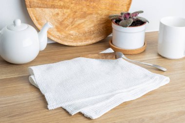 Beyaz çay seti, ahşap kesim tahtası ve ahşap bir masanın üzerinde saksı bitkisi olan düzenli bir mutfak sahnesi..