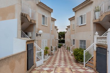 İspanya 'nın Torrevieja kentindeki güneşten sırılsıklam olmuş bir iskan caddesinde, huzurlu bir Akdeniz mahallesinin özünü yansıtan fayanslı yolları ve beyaz korkulukları olan büyüleyici apartmanlar bulunuyor..