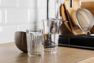 Temiz bir bardak ve mutfak tezgahında suyla dolu bir ölçü kabı.