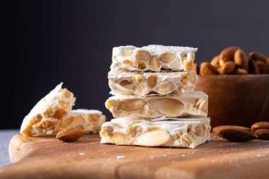 Geleneksel bir İspanyol şekerlemesi olan dört adet sert beyaz turon parçasının yakın plan çekimi, tipik olarak Noel sezonunda yapıldı. Her dilim, yoğun, çıtır çıtır bal ve yumurta beyazı karışımına gömülmüş kavrulmuş bademleri ortaya çıkarıyor.