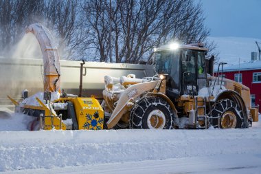 Akureyri İzlanda - 21 Kasım. 2024: Kar temizleme makineli yükleyici bir karavana kar üflüyor