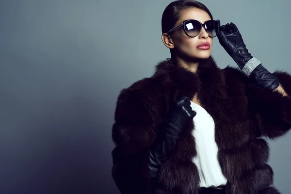 Hermoso modelo glam con blusa de seda blanca, abrigo de sable, guantes de cuero, gafas de sol y conjunto de pulsera de lujo, anillo y cadena de plata con colgante . —  Fotos de Stock