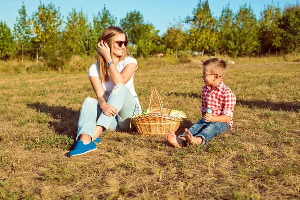 Pequeno menino bonito está fazendo piquenique com sua jovem mãe bonita . — Fotografia de Stock