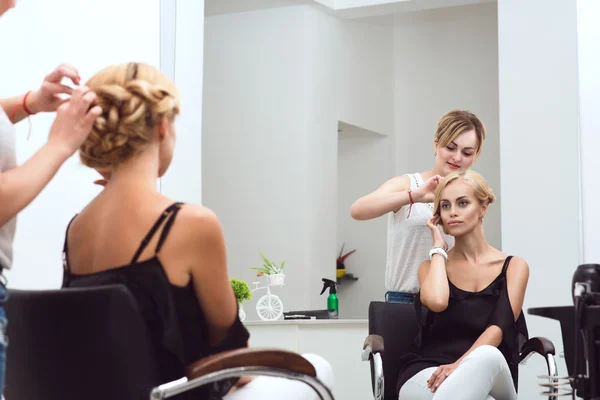 Female hair stylist braids her beautiful client's hair at the beauty salon — Stock Photo, Image