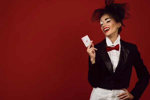 Portréja egy fiatal gyönyörű hölgy krupié Joker gazdaság kártya egy ász, és nevetve a kép — Stock Fotó