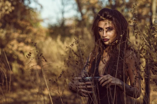 Πορτρέτο της γοητευτικό επικίνδυνες νεαρή μάγισσα κρατώντας μια κατσαρόλα με μαγικό φίλτρο στο δάσος και κοιτάζοντας κατευθείαν με το διαπεραστικό βλέμμα — Φωτογραφία Αρχείου