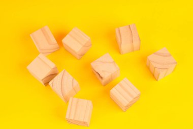 Dağıtılmış ahşap bloklar parçalanma ve düzensizliği, devam eden bir iş akışını ve parçaları birleştirme mücadelesini temsil ediyor..