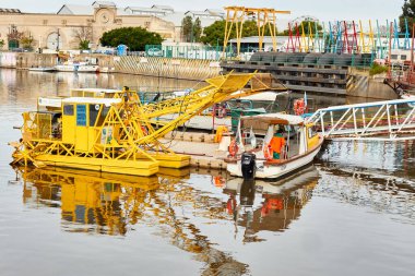 Sarı tarama makinesi ve devriye botu Riachuelo kanalı Buenos Aires, Arjantin - 3 Haziran 2024.
