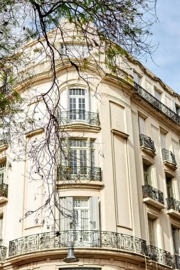 Ağaç dalları tarafından çerçevelenmiş zarif köşe binası.