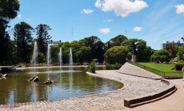 Parque Centenario 'nun yeşil alanları ve güneşli bir günde huzurlu bir şehir parkının keyfini çıkaran insanların geniş bir manzarası. Buenos Aires, Arjantin 24 Kasım 2025