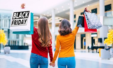Siyah Cuma 'nın yazılı olduğu ellerinde alışveriş torbalarıyla renkli elbiseli iki genç kadının arka plan fotoğrafı..