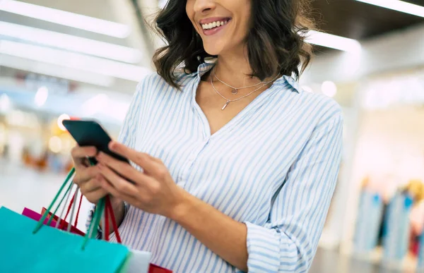 색깔의 쇼핑백을 복장을 여성이 센터를 스마트폰을 사용하고 — 스톡 사진