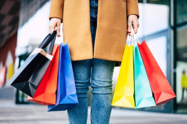 Çok sayıda renkli alışveriş çantaları olan, şık telefon ve kredi kartıyla şık bir genç bayan siyah cuma günü alışveriş merkezinde yürürken...