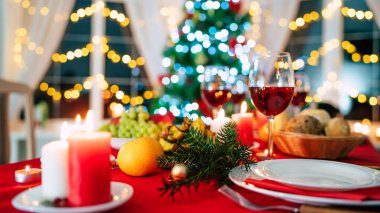 Parlak dekore edilmiş büyük yeni yıl sofrasında arka planda Noel ağacı var.