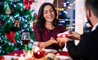 Mutlu, güzel, aşık bir çift Noel masasında oturmuş kadehlerinden şarap içiyor..