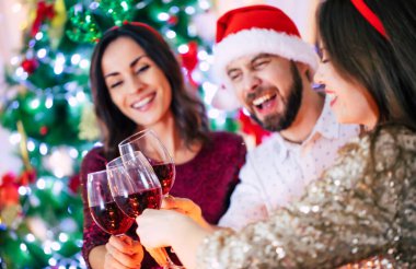 Bir grup mutlu ve güzel arkadaş bir Noel partisinde ellerinde kadehlerle yemek yerken eğleniyorlar..