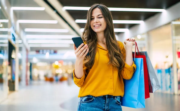 가방을 행복하고 아름다운 여성이 금요일 쇼핑몰을 스마트폰을 사용하고 있습니다 — 스톡 사진