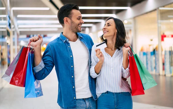 ショッピングモールを歩いている間に手に紙の袋とクレジットカードで愛や家族で美しい幸せな興奮したカップル — ストック写真