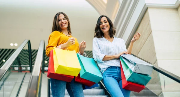 Güzel, mutlu ve heyecanlı genç kız arkadaşları alışveriş merkezinde dolaşıyorlar.