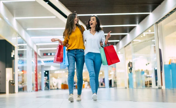提着纸袋的年轻女友们正在购物中心里走来走去 — 图库照片