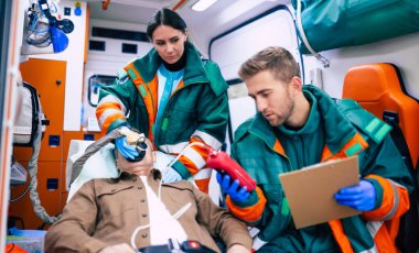 Doktorların acil durumu ya da sağlık görevlileri, yaşlı bir hastayla ambulansta sedyede yatarken birlikte çalışıyorlar..