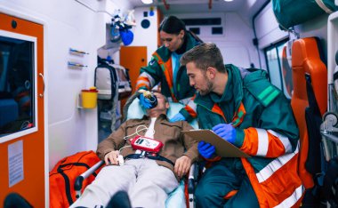 Doktorların acil durumu ya da sağlık görevlileri, yaşlı bir hastayla ambulansta sedyede yatarken birlikte çalışıyorlar..