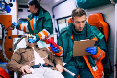 Doktorların acil durumu ya da sağlık görevlileri, yaşlı bir hastayla ambulansta sedyede yatarken birlikte çalışıyorlar..