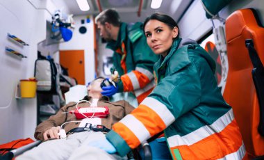 Doktorların acil durumu ya da sağlık görevlileri, yaşlı bir hastayla ambulansta sedyede yatarken birlikte çalışıyorlar..